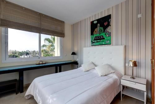 a bedroom with a large white bed and a window at Apartamento Costalita in Estepona