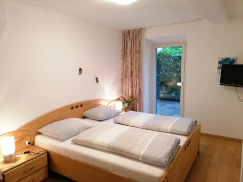 a bedroom with two beds and a television and a window at Pension Sunnhofer in Vilpiano