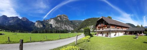 a house in a field with mountains in the background at Landhaus Algerhof in Abtenau