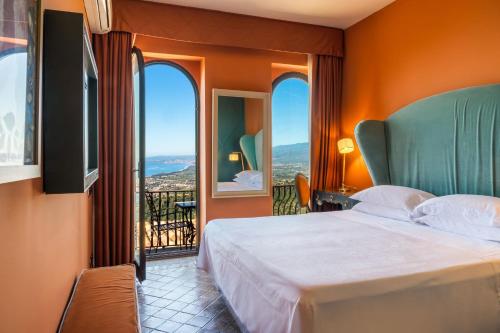 a bedroom with a bed and a balcony at Hotel Villa Ducale in Taormina