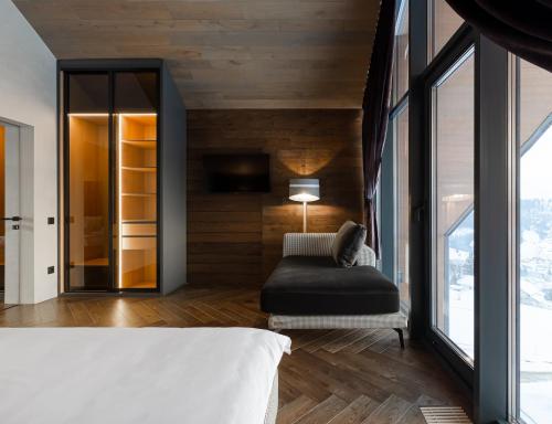 a bedroom with a bed and a chair and windows at Villas Fomich in Bukovel