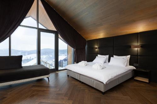a bedroom with a large bed and a large window at Villas Fomich in Bukovel
