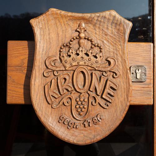 a wooden sign that says one extra tiers on a wooden bench at Hotel & Restaurant Krone in Kestert