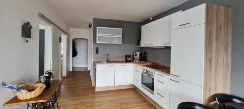 eine Küche mit weißen Schränken und einem Holztisch in der Unterkunft Schwarzwald-Blick Lenzkirch-Saig in Lenzkirch