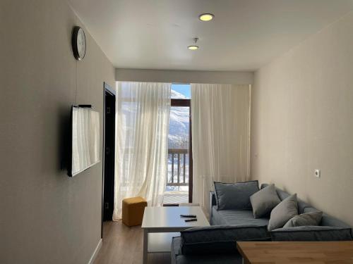 a living room with a couch and a large window at Apartment Qumli in Gudauri