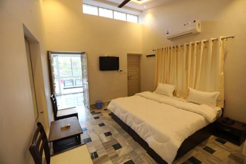 - une chambre avec un lit doté de draps blancs et une fenêtre dans l'établissement CASA Orchard House, à Mount Âbû