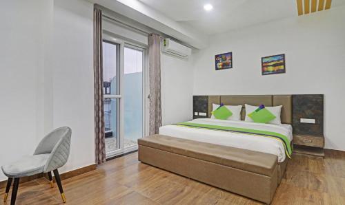 a bedroom with a bed and a chair and a window at Treebo Kanopy Greens in Dehradun