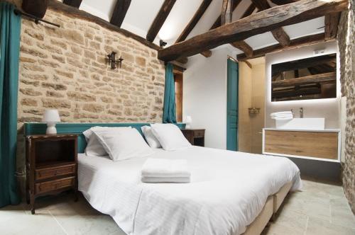 - une chambre avec un lit blanc et un mur en briques dans l'établissement Jardin des Sens, la Rente d'Eguilly, à Éguilly