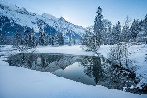 a snow covered lake with mountains in the background at Eden Hotel, Apartments and Chalet Chamonix Les Praz in Chamonix-Mont-Blanc