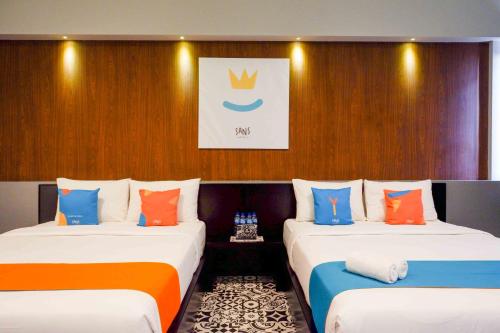 two beds in a room with a wall at Sans Hotel Empress Simpang Lima in Semarang