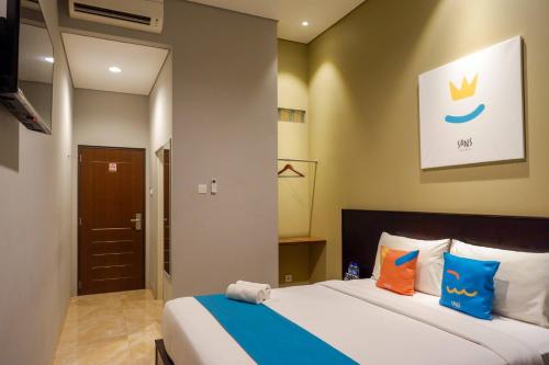 a bedroom with a king sized bed with blue and orange pillows at Sans Hotel Empress Simpang Lima in Semarang