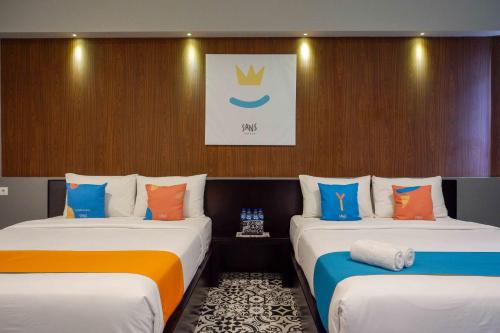 two beds in a hotel room with at Sans Hotel Empress Simpang Lima in Semarang