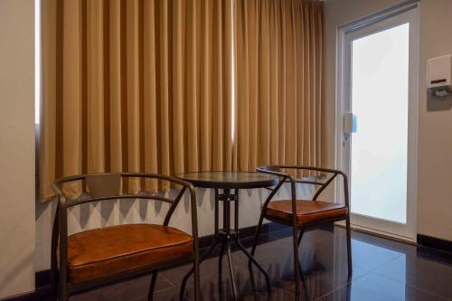 a room with two chairs and a table and a window at Sans Hotel Empress Simpang Lima in Semarang