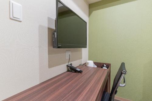 a room with a desk with a television on a wall at ibis Budget Osaka Umeda in Osaka