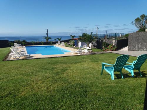 two green chairs sitting in the grass near a swimming pool at Azores Residence in Pesqueiro