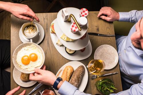 ein Tisch mit Eiern und Brot und Menschen, die Essen essen in der Unterkunft Nobel Hotel Ameland in Ballum