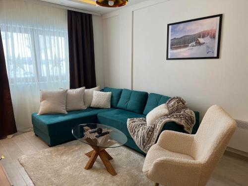 ein Wohnzimmer mit einem blauen Sofa und 2 Stühlen in der Unterkunft Milmari Apartman Haski N55 in Kopaonik