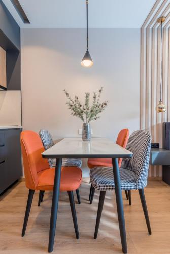 a dining room table with orange chairs and a vase with flowers at New Gudauri Atrium Ski and Dream Apartments in Gudauri