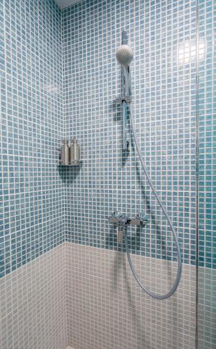a bathroom with a shower with blue tiles on the wall at New Gudauri Atrium Ski and Dream Apartments in Gudauri
