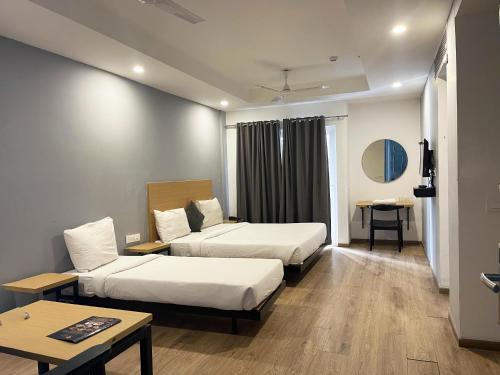 a hotel room with two beds and a table at The Roseman Hotel and Suites in Ghaziabad