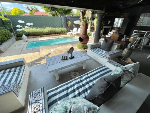 a patio with two couches and a table and a pool at The Minimalist Studio B in Benoni