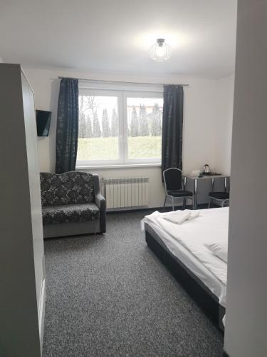 a bedroom with a bed and a chair and a window at Pokoje Gościnne MAGNOLIA in Zalewo