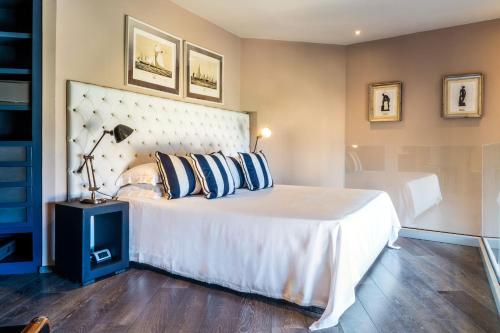 a bedroom with a large white bed with blue pillows at Hotel Villa Carlotta in Taormina