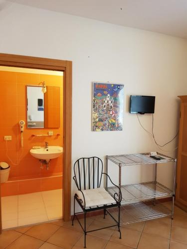 bagno con sedia, lavandino e specchio di B&B Soriano44 a Napoli