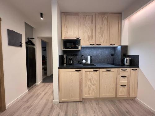 a kitchen with wooden cabinets and a microwave at Apartmány Panorama Harrachov in Harrachov