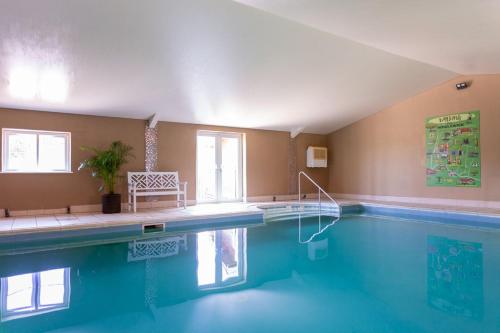 a large swimming pool with blue water in a room at Middlewick Holiday Cottages in Glastonbury