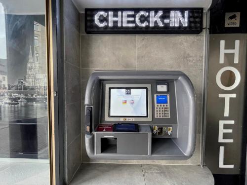 Une machine à atm dans un bâtiment avec un panneau. dans l'établissement SMARTY Cologne Dom Hotel - Boardinghouse - KONTAKTLOSER SELF CHECK-IN, à Cologne