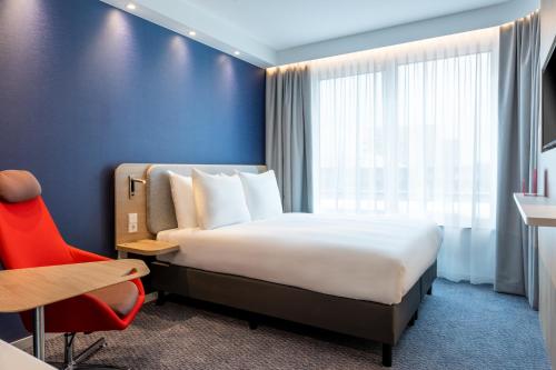 a hotel room with a bed and a red chair at Holiday Inn Express - Almere by IHG in Almere