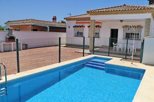 a swimming pool in front of a house with a tennis court at Chalet Pinar de Roche in Conil de la Frontera