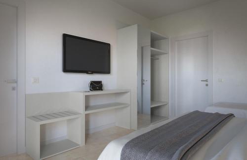 a white bedroom with a television on a wall at Hotel Aron in Rimini