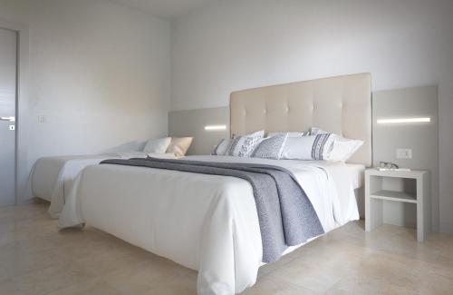 uma grande cama branca com lençóis e almofadas brancos em Hotel Aron em Rimini