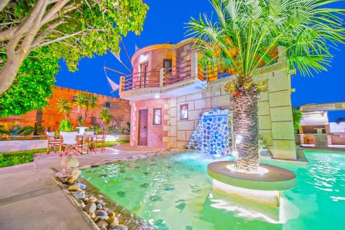 a house with a palm tree in the middle of a pool at Anemomili Village in Kissamos