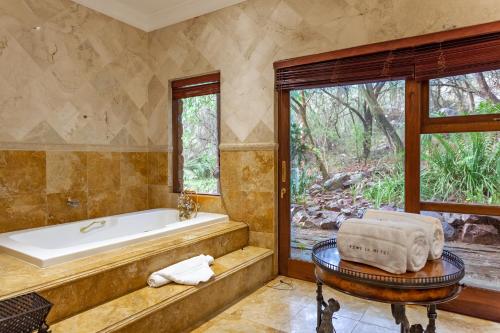 a bathroom with a tub and a large window at Lejwe La Metsi Private Reserve in Bela-Bela
