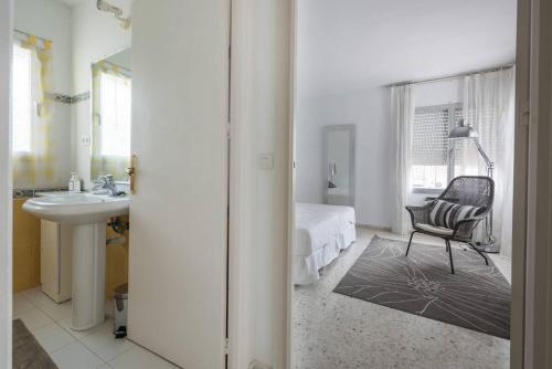 1 dormitorio con cama, silla y lavamanos en Villa Mimosa, en Marbella