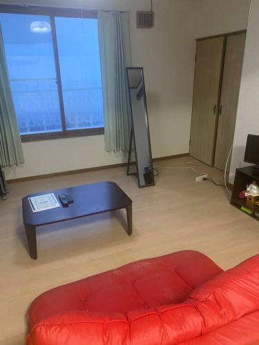 Sala de estar con sofá rojo y mesa de centro en 旭山動物園、美瑛、車で30分、旭川中心部徒歩3分 en Asahikawa