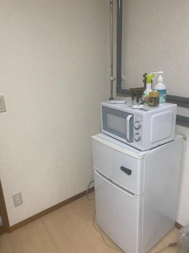 a microwave sitting on top of a white refrigerator at 旭山動物園、美瑛、車で30分、旭川中心部徒歩3分 in Asahikawa