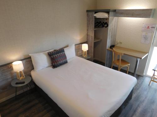 a bedroom with a large white bed with two lamps at Brit Hotel Ariès, Argentan in Argentan