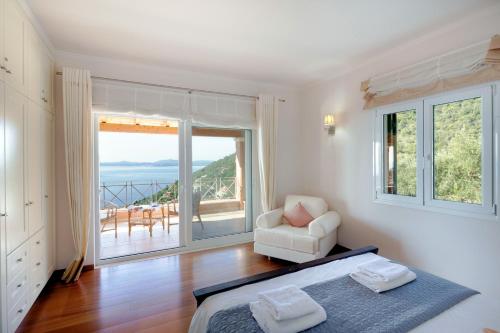 a bedroom with a bed and a chair and a balcony at Villa Aphrodite in Agní