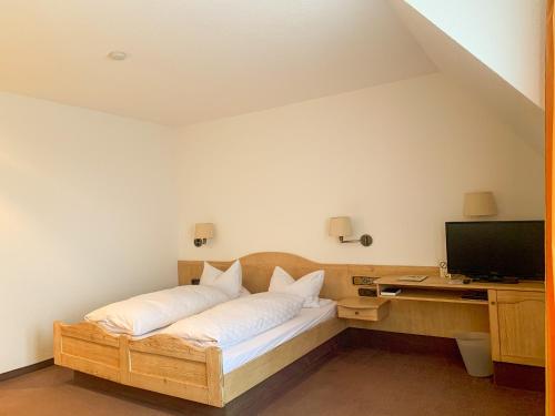 a room with a bed with a desk and a television at Landhotel Bauernschmitt in Pottenstein