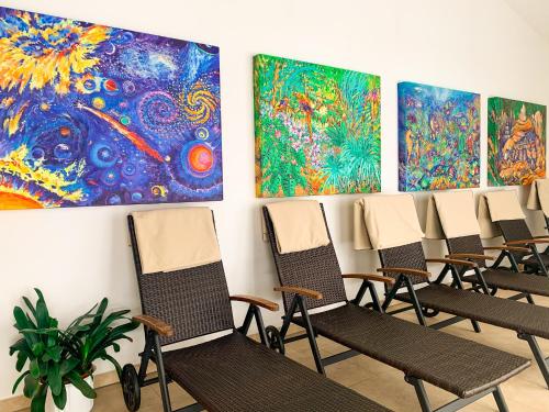 a row of chairs in a room with paintings on the wall at Landhotel Bauernschmitt in Pottenstein