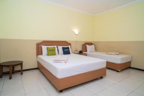 a bedroom with two beds and a table at Urbanview Hotel de Kopen Malang by RedDoorz in Malang
