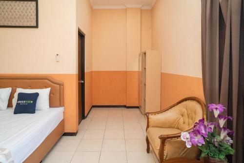 a bedroom with a bed and a chair and flowers at Urbanview Hotel de Kopen Malang by RedDoorz in Malang