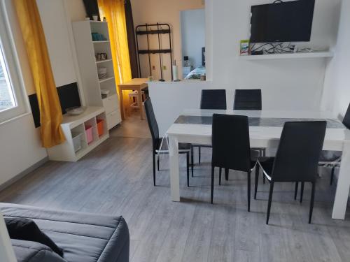 a dining room with a white table and black chairs at appartement individuelle refais a neuf,ds maison de maître,6 couchages dont un lit kingsize,cuisine avec lave vaisselle,rue privative pour se garer, accessibilité au jardin in Le Havre