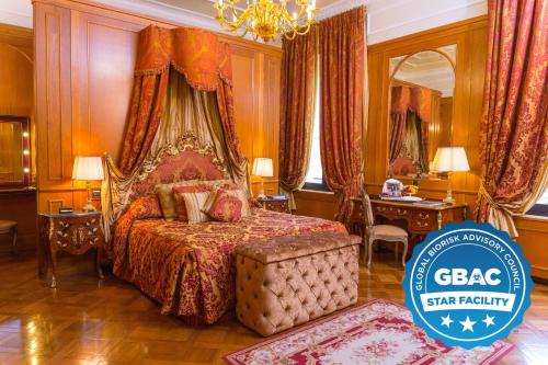 a bedroom with a bed and a desk and a chandelier at Grand Hotel Majestic gia' Baglioni in Bologna