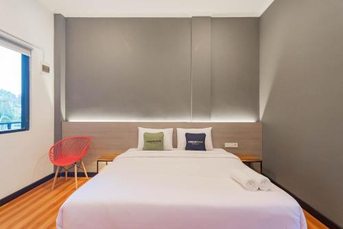 a bedroom with a large white bed and a red chair at Urbanview Hotel Sagara Bogor in Bogor