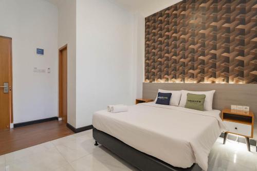 a bedroom with a large bed and a large wall at Urbanview Hotel Sagara Bogor in Bogor